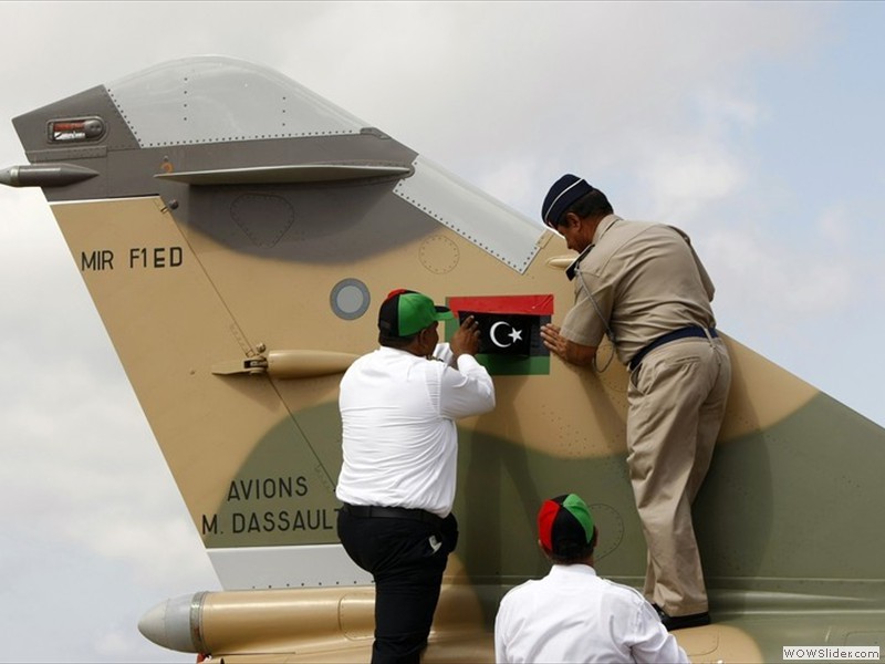 Libyan Air Force Brigadier General Mohammed Rajab (R) replaces the all-green Gaddafi-era Libyan flag on the tail of a Libyan Air Force Mirage F1 fighter jet with a Kingdom of Libya flag  (2)